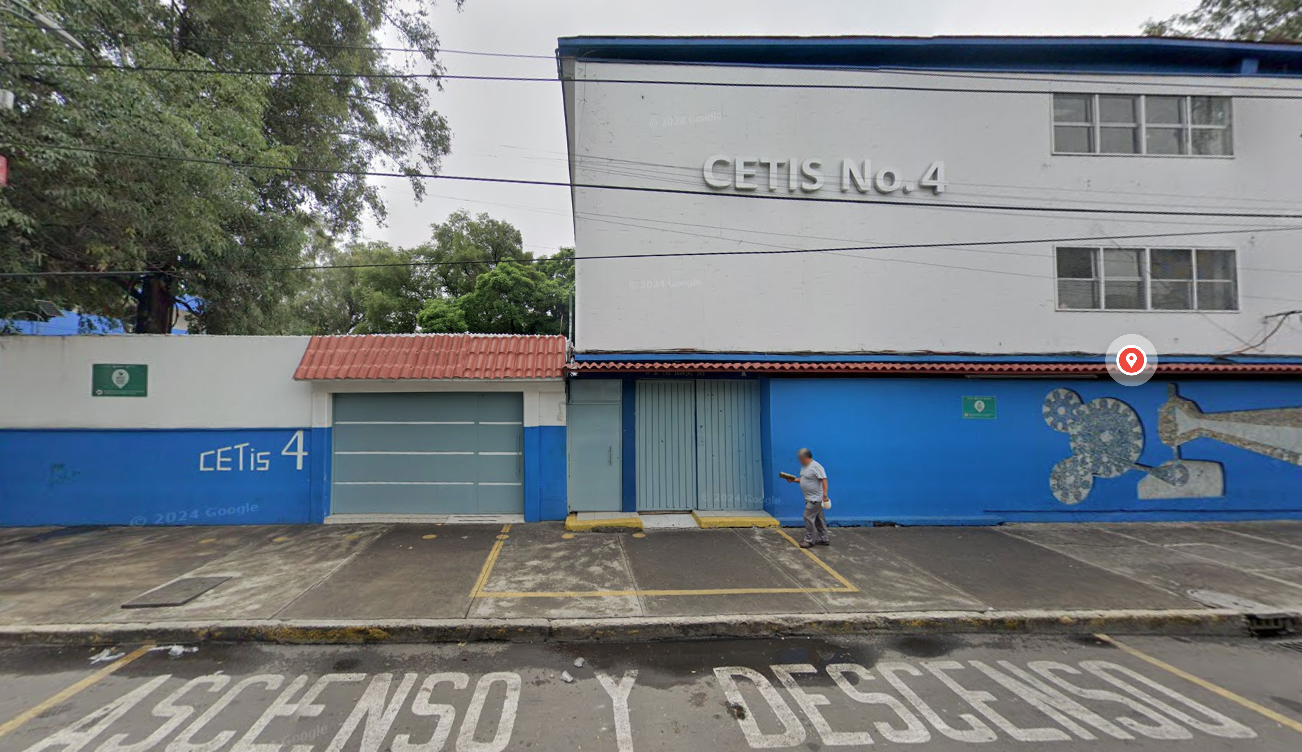 Fotografía en la que se muestra la fachada del plantel, conformada por muros de color blanco y azul. En la parte inferior, a la mitad de la foto hay un portón metálico a través del cual se puede ingresar a las instalaciones. Arriba del portón hay unas letras grandes que dicen CETIS NÚMERO 4.